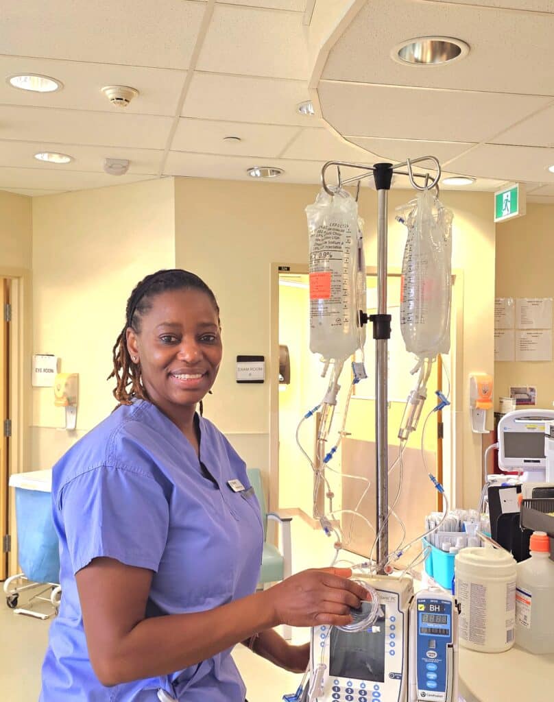 nurse smiling at work with an IV bag