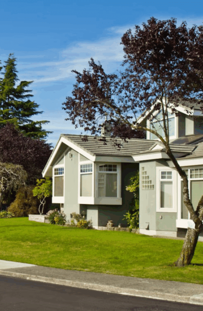 Outside of a house on a sunny day with green grass and trees in the Edmonds neighbourhood of Burnaby, B.C., Canada.