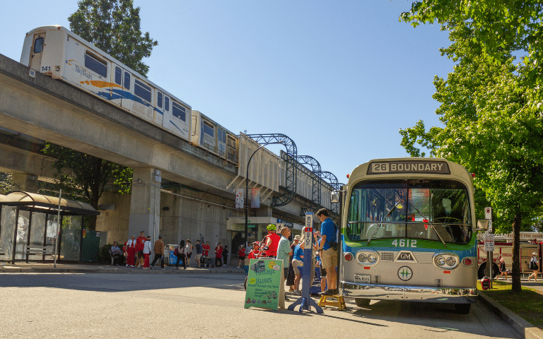 Skytrain and bus station in Burnaby with people walking around.