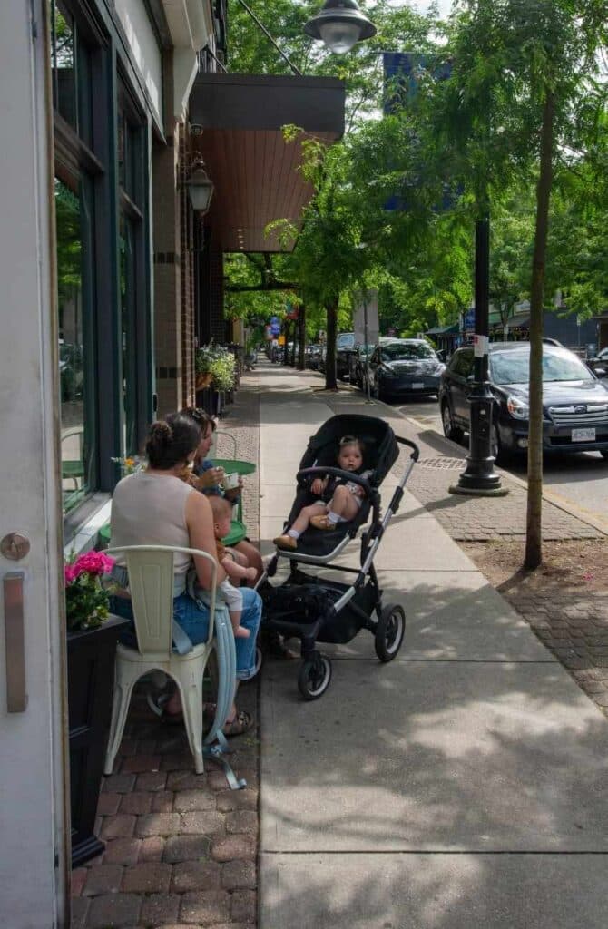 Two woman and a baby girl in a stroller sitting outside a cafe on the sidewalk in Fort Langley, B.C.