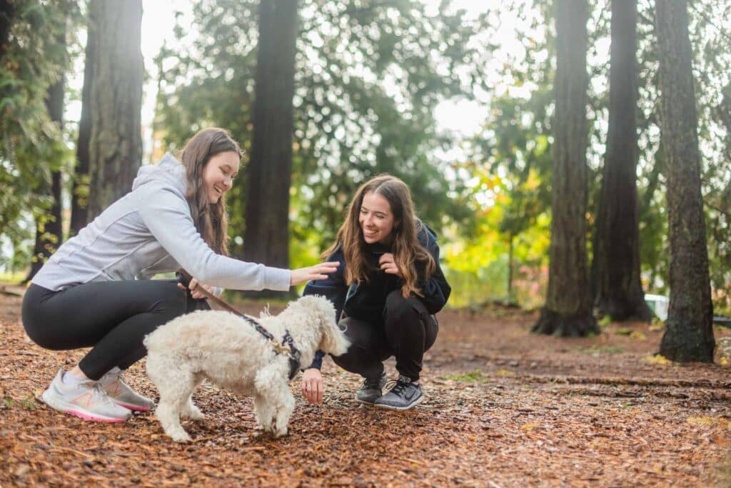 Two ladies petting a dog in the park.