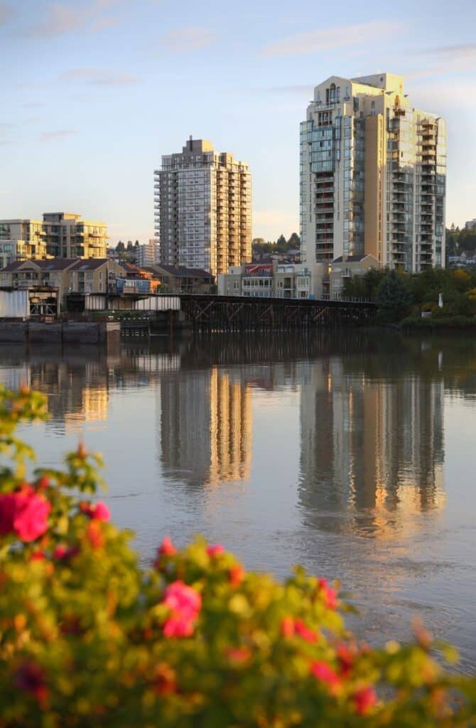Scenic view of Queensborough neighbourhood in New Westminster with high rises, pond of water and flowers.