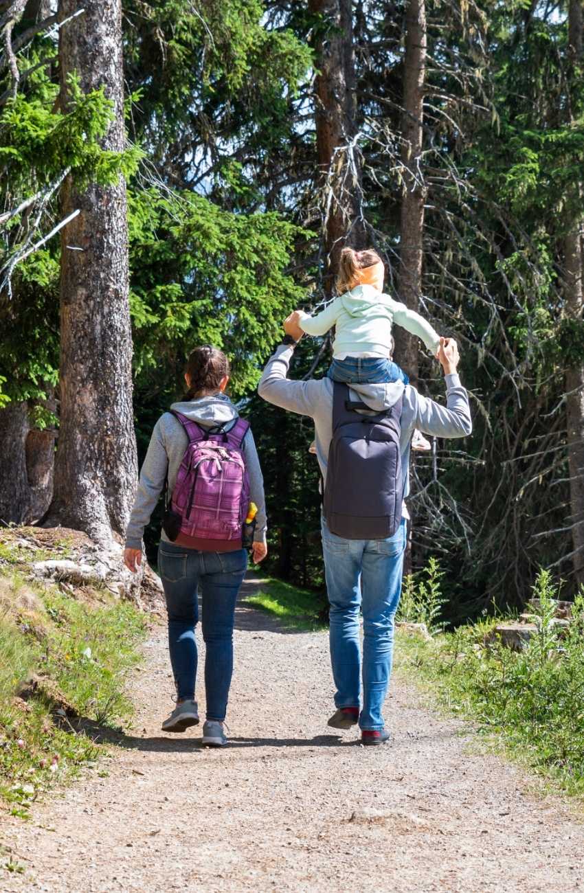 Couple hiking with child on dad's shoulders.